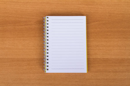 Top view of blank, white, open notebook on wood .