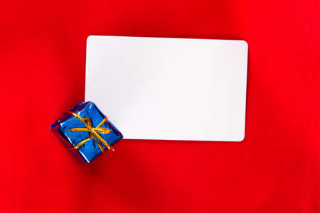 White blank christmas card with gift box on red .の写真素材