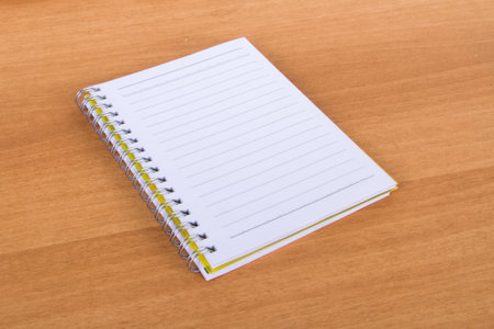 Top view of blank, white, open notebook on wood .