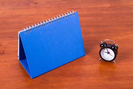 Desk calendar mock up with alarm clock on table.