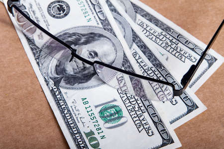 Pair of eyeglasses on one hundred dollar banknotes.の写真素材