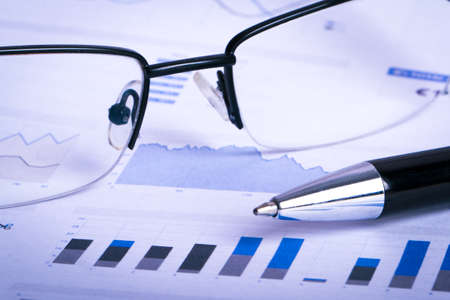 Financial data chart graphs and analysis with pen, eye glasses on business table.の写真素材