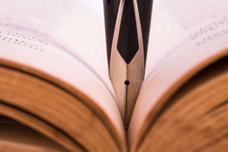 Close up, macro view of black fountain pen between history book sheets with depth of field.の写真素材