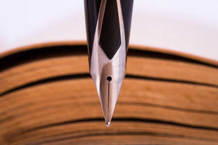 Macro and front view of fountain pen, old history book behind.の写真素材