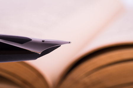 Macro and front view of fountain pen, old history book behind.の写真素材