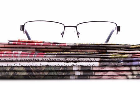 Stack of newspapers and eye glasses, isolated on white background.