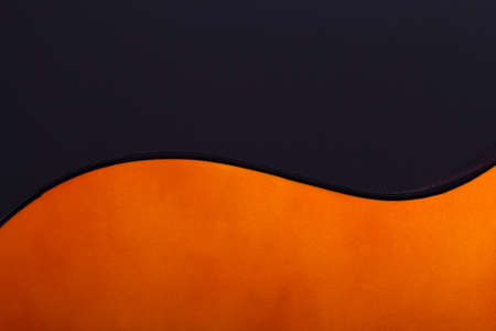 Detail view of orange wooden classical acoustic guitar over black background.の写真素材