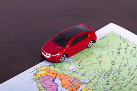 Small, toy car for travel concept on colorful map.