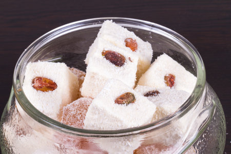 Turkish delights in glass bowl on wooden table.