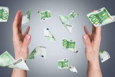 One hundred euro money banknotes flying and falling on young male hands.の写真素材