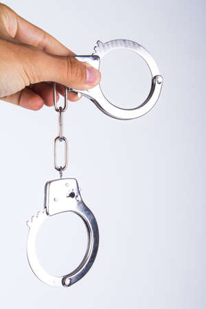 Hand holding handcuffs, isolated on white background.の写真素材