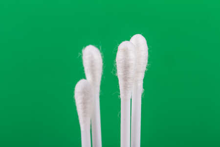 White cotton swabs on green background.の写真素材
