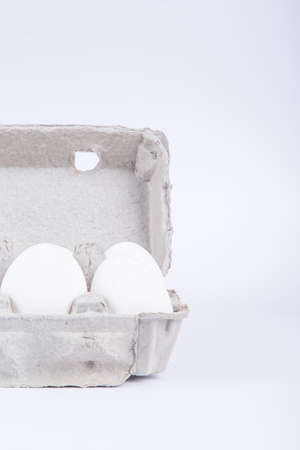 Two white eggs in carton with front view, isolated on white background.の写真素材