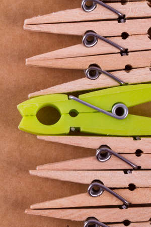 Detailed close up top view of wooden clothespins with a green one, on paperboard background.の写真素材