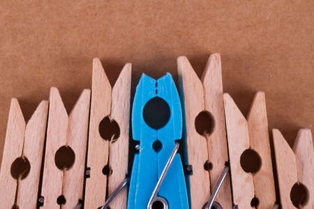 Detailed close up top view of wooden clothespins with a blue one, on paperboard background.の写真素材