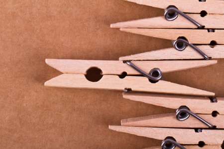 Detailed close up top view of wooden clothespins with one ahead, on paperboard background.