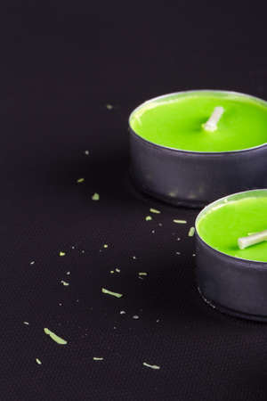 Close up detailed front view of two green candles, on black background.の写真素材