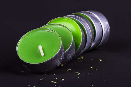 Close up detailed front view of green candles, on black background.の写真素材