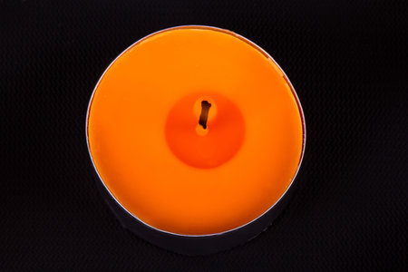 Close up detailed top view of orange candle, on black background.の写真素材