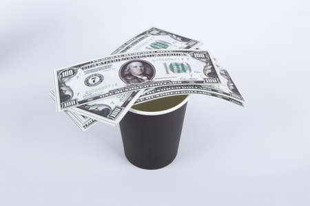 Close up top view of black paper glass with banknotes of one hundred dollar on, isolated on white background.の写真素材