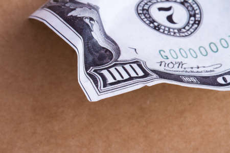 Close up detailed top view of crumpled one hundred dollar bannotes, on brown background.の写真素材