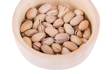 Close up top view of pistachio in a wooden bowl, isolated on white background.の写真素材