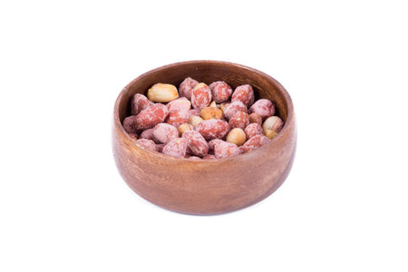Close up view of peanut in a wooden bowl, isolated on white background.