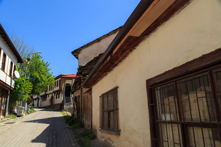 Close up detailed view of a white house in the village with grilled window, under blue sky.