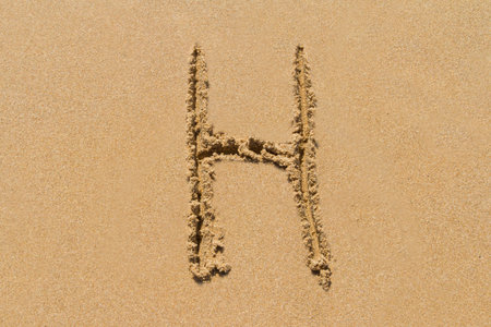 Letter H of the alphabet written on sand with upper case.の写真素材