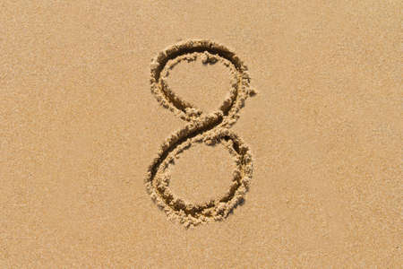 The number 8 drawn on sand at the beach, holiday concept background.の写真素材