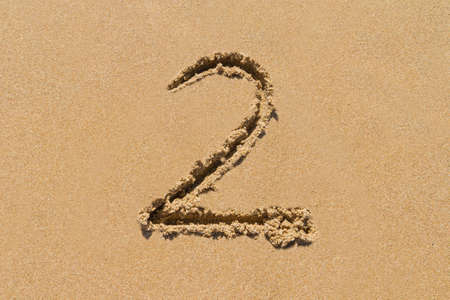The number 2 drawn on sand at the beach, holiday concept background.の写真素材