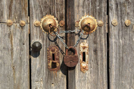 Close up front view of wooden old door, closed with chains and locked with padlock.の写真素材