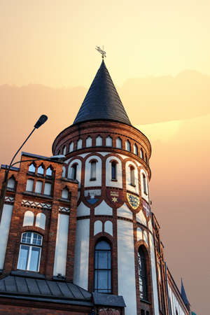 Close up bview of historical old house building with a small tower, on sunset or sunrise sky background.の写真素材