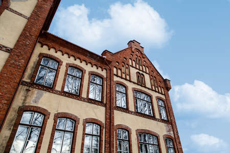 Close up bottom view of stone wall house building, on cloudy blue sky background.の写真素材