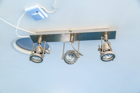 Close up bottom view of spot led llights with cables in ceiling, on blue background.の写真素材