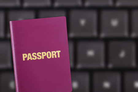 Close up detailed front view of a passport on blury keyboard as background.