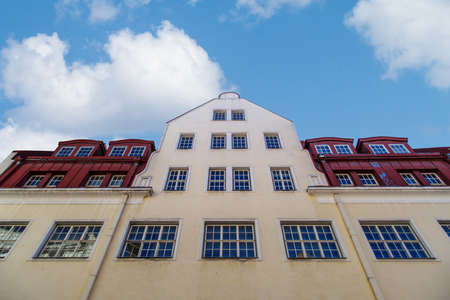 Close up bottom view of old stone building with big windows, on cloudy blue sky background.の写真素材