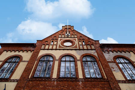 Close up detailed bottom view of stone wall house building, on cloudy blue sky background.の写真素材