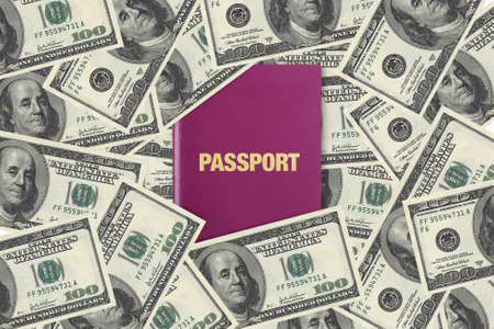 Close up front view of a passport, among one hundred dollar banknotes as background.の写真素材
