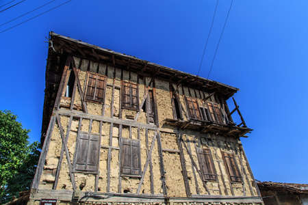 Bottom view of historical old and abandoned wooden and stone house of Yoruk Village in Safranbolu, Karabuk, on blue sky background.の写真素材