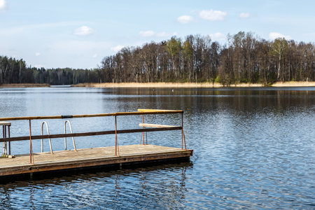View of wooden pier inside lake, scenic view of reflection of the clouds and trees on lake, with cloudy blue sky background.の写真素材
