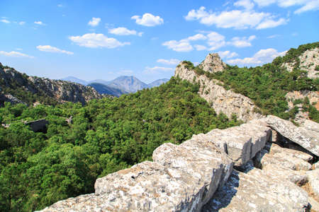 View of high mountains with small floiage and rocks around, on cloudy blue sky background.の写真素材