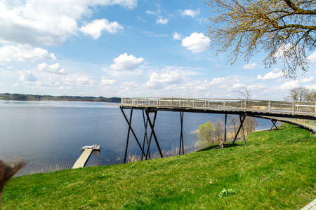 View of wooden old pier on lake among trees, on cloudy blue sky background.の写真素材