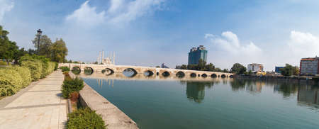 Side view of historical old stone bridge of Adana on Seyhan river, on cloudy blue sky background.の写真素材