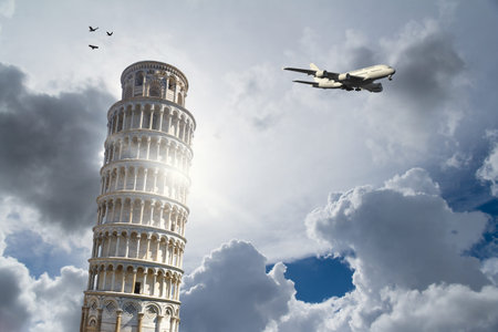 View of historical Pisa Tower in Cathedral Square of Pisa, Italy with a plane, on cloudy blue sky...