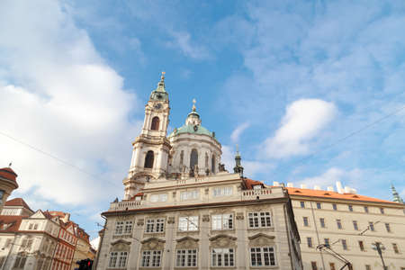 Close up detailed dome view of historical St Nicholas Church in Prague, on cloudy blue sky background.の写真素材