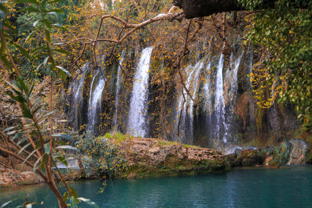 View of Kursunlu Waterfall in Antalya, flowing from high, with green trees and plants around.