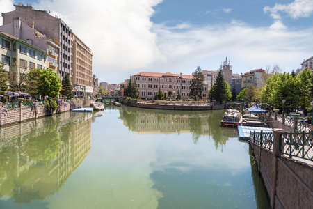 ESKISEHIR, TURKEY - APRIL 16, 2016 : View of Porsuk river flowing along the city in Eskisehir with trees and houses around on blue sky background.のeditorial素材