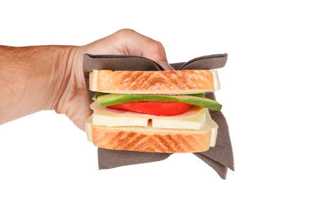 View of a sandwich with cheese, tomato and cucumber holding on hand, isolated on white background.の写真素材