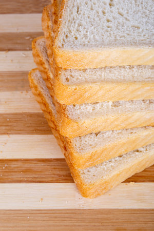 Slices of toast bread on breadboard, isolated on white background.